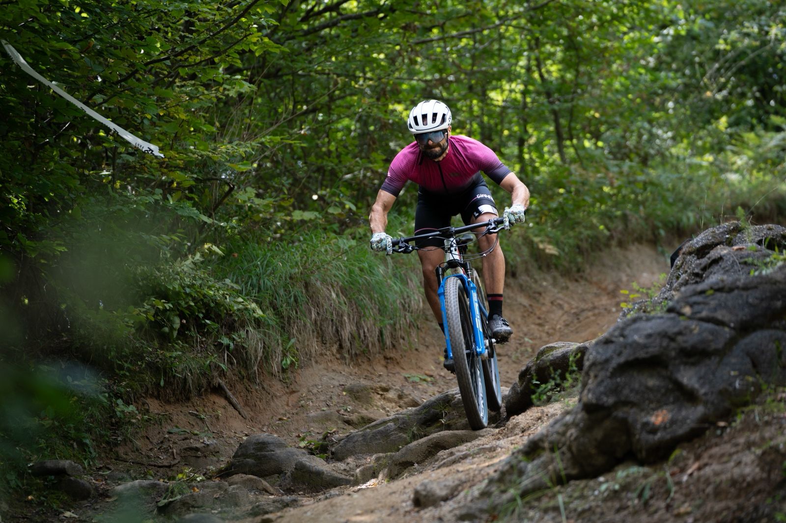 Mountain biker racing down a steep, dusty trail